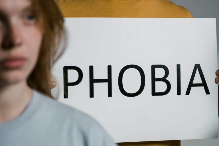 A close-up of a person holding a sign with the word 'Phobia,' illustrating mental health themes.